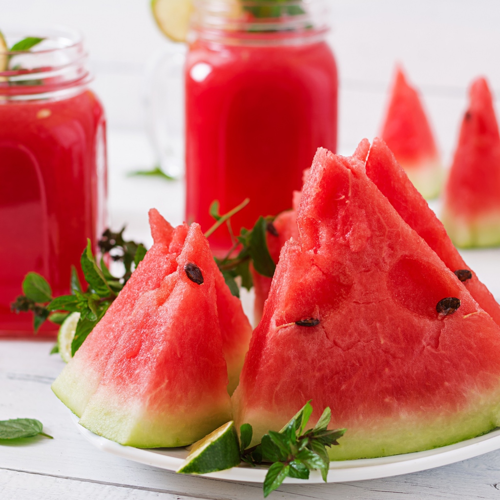 Куски арбуза с мятой на столе с соком 