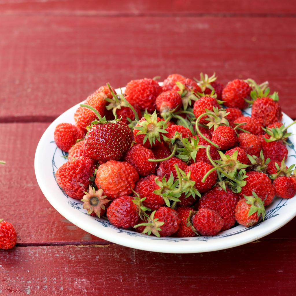 Тарелка со спелой домашней клубникой на столе