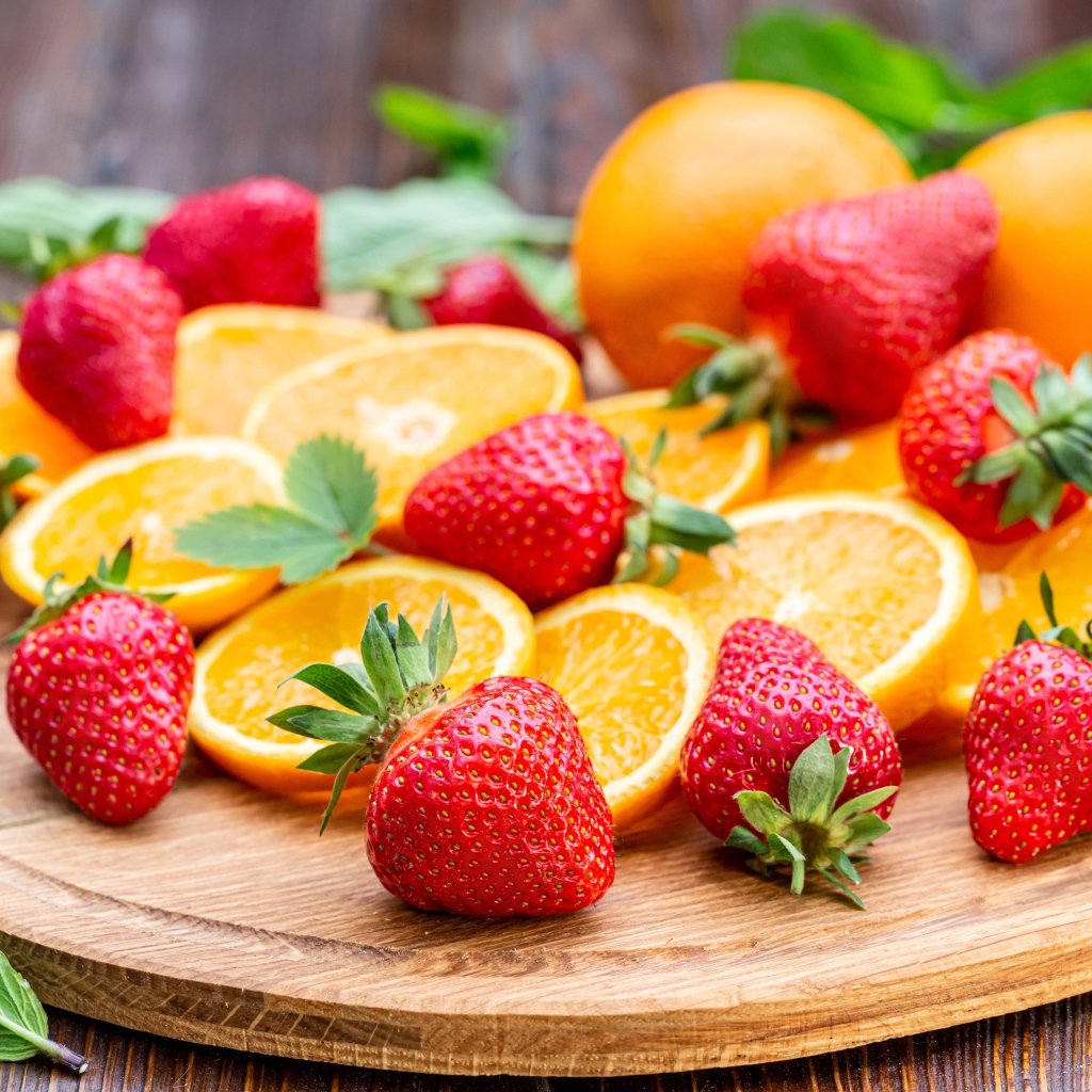 Красная свежая клубника на доске с кусочками апельсина