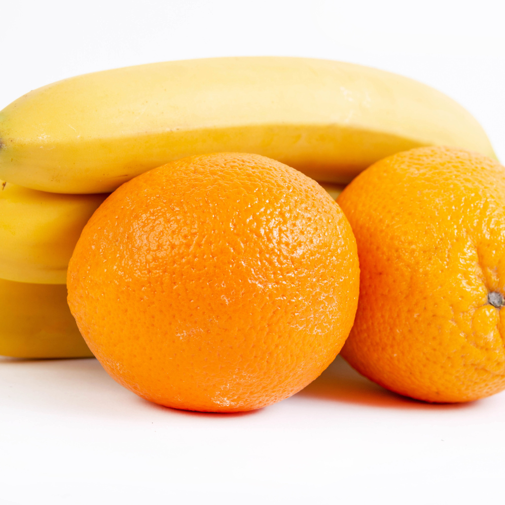 Спелые апельсины и бананы на белом фоне 