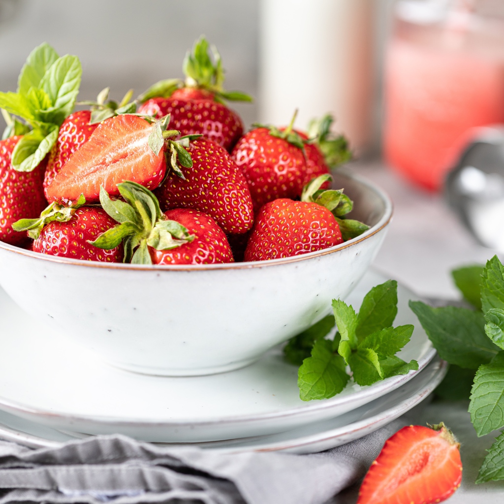 Спелая клубника с мятой на столе в белой тарелке 