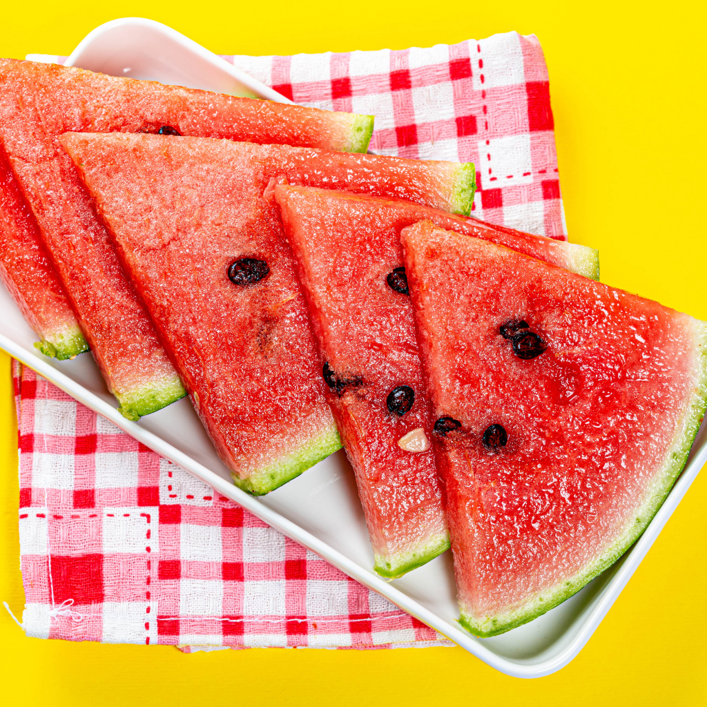 Кусочки сочного арбуза в тарелке на желтом столе