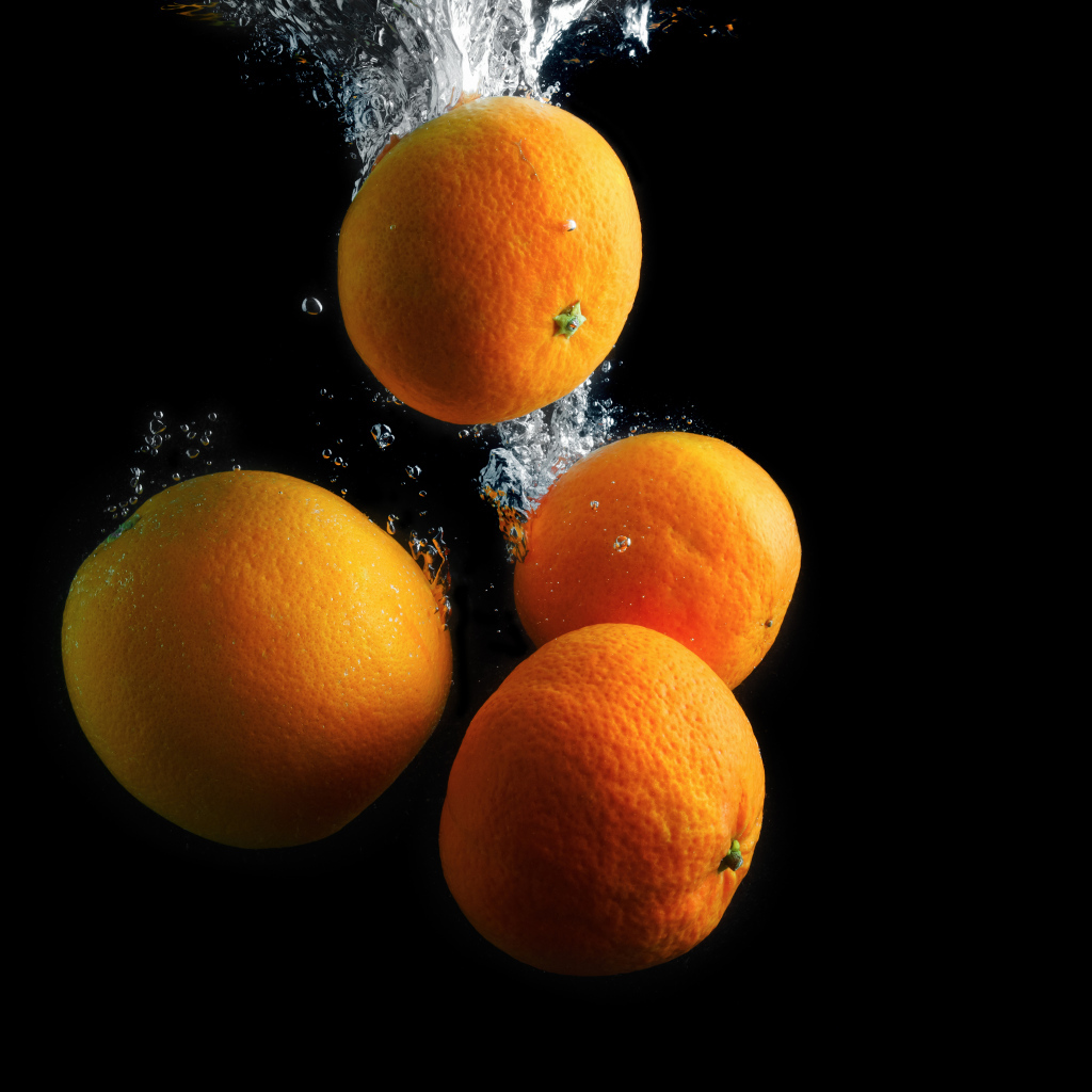 Мандарины и апельсины в воде на черном фоне