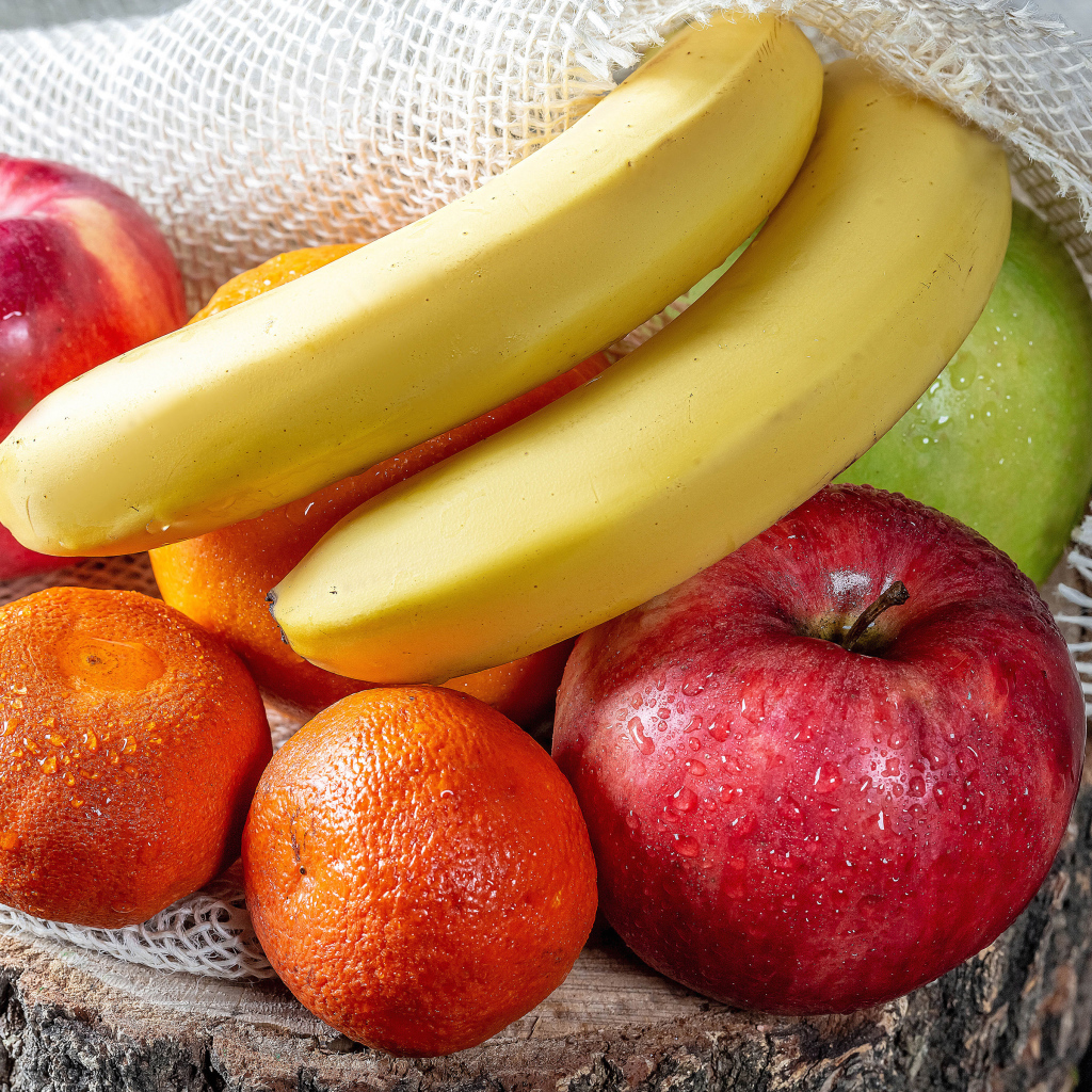 Мокрые бананы, яблоки и мандарины на столе 