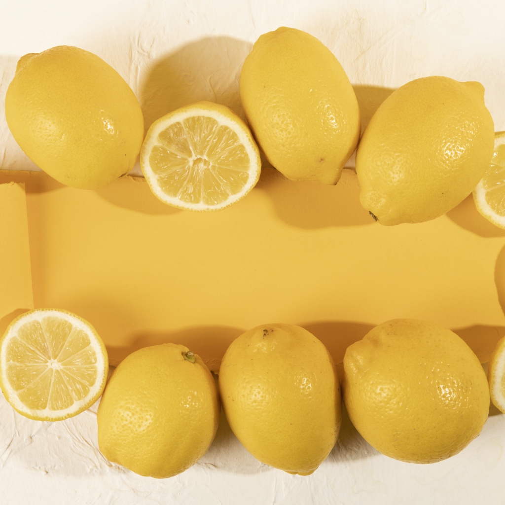 Желтые лимоны на белом фоне с листом бумаги