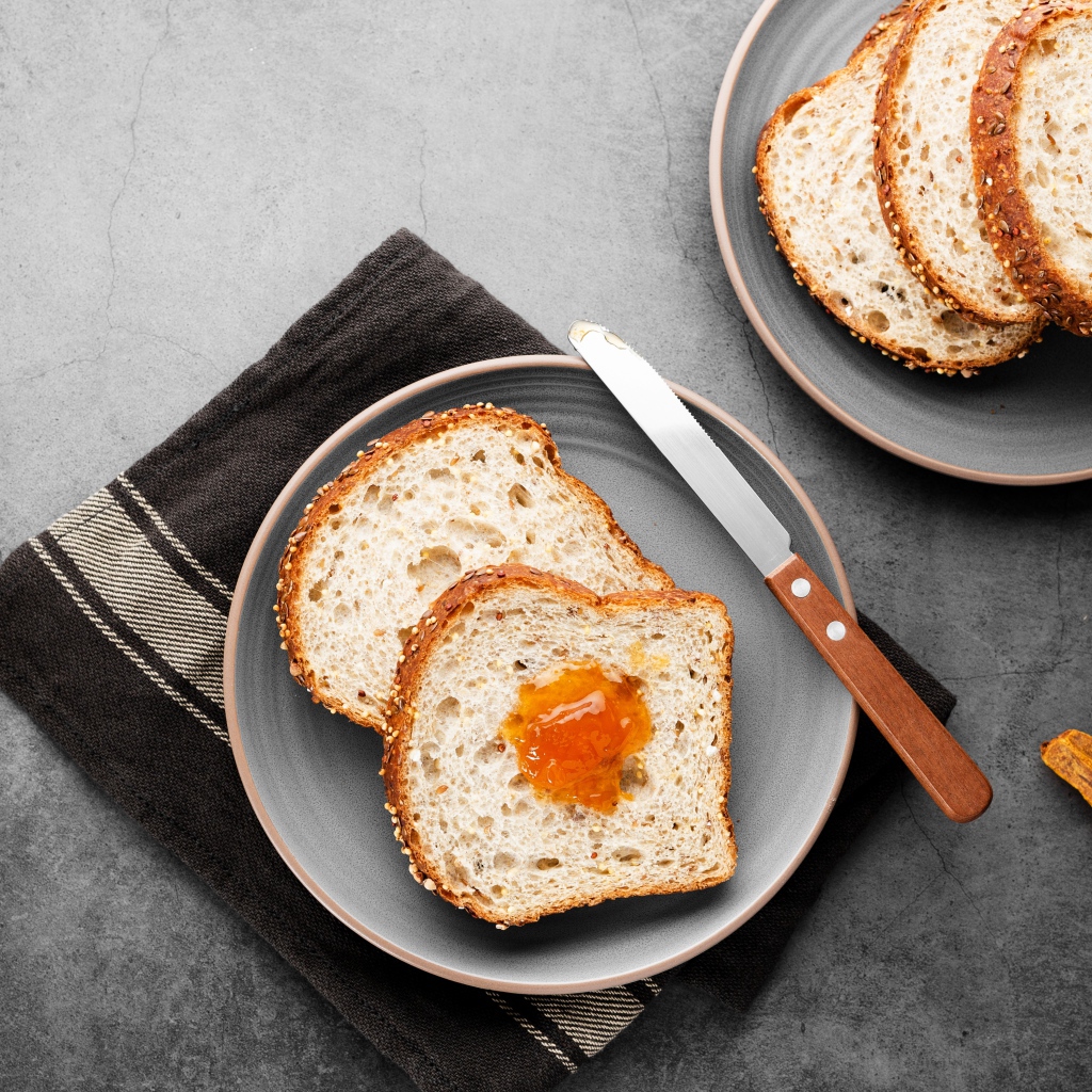 Куски хлеба с джемом на сером столе 