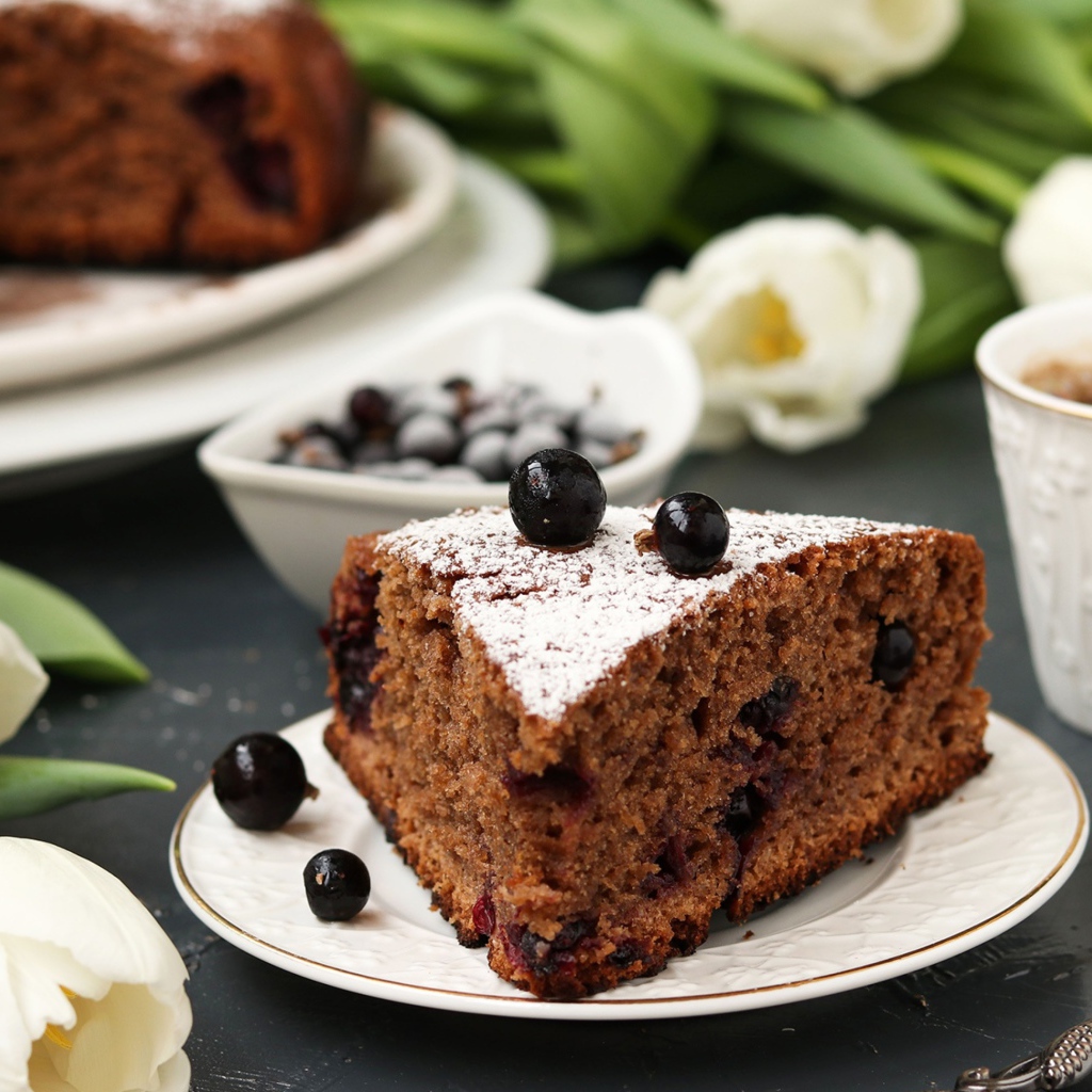 Кусок пирога со смородиной на столе с тюльпанами 