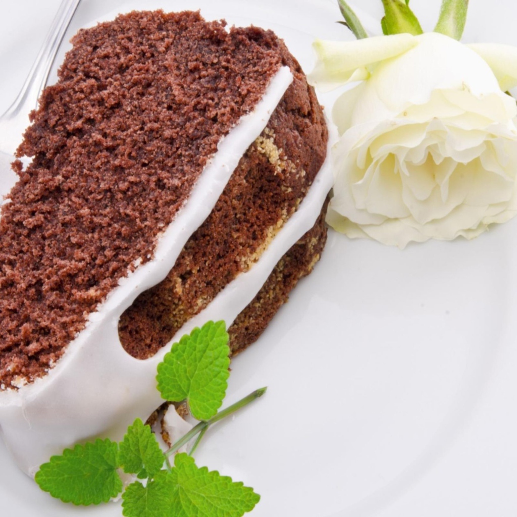 Кусок шоколадного пирога на тарелке с белой розой 