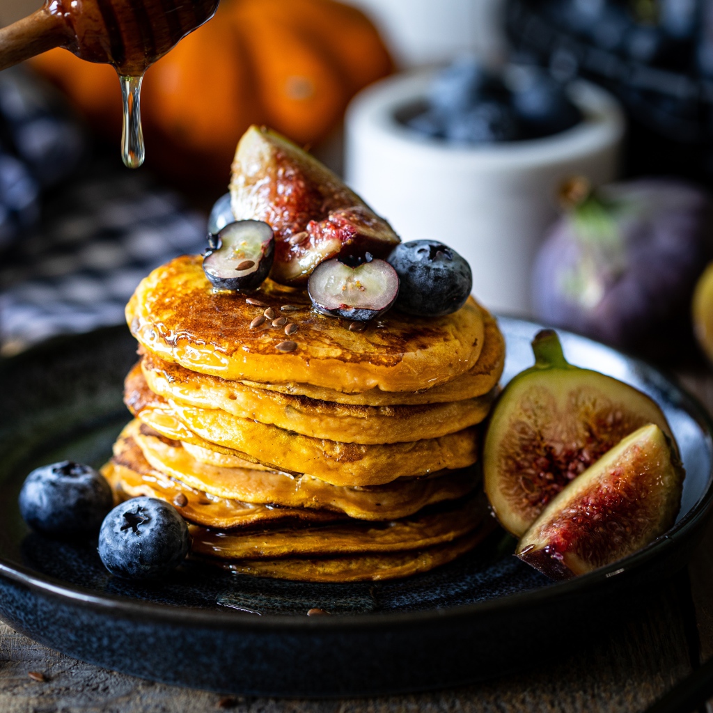 Аппетитные оладьи на тарелке с ягодами черники и инжиром