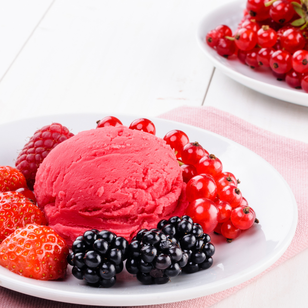Шарик фруктового мороженого с ягодами на белой тарелке