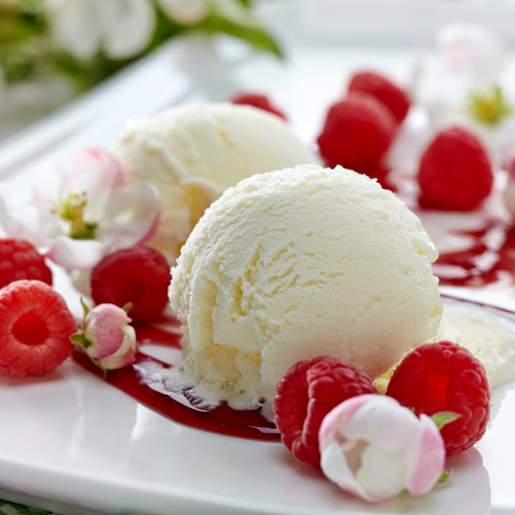 Шарики сливочного мороженого на тарелке с малиной и цветами
