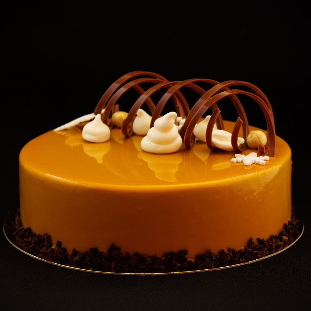 Красивый глянцевый оранжевый торт на черном фоне