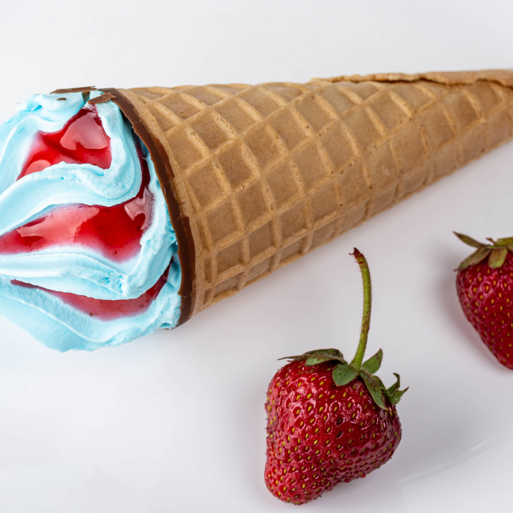 Рожок с голубым мороженым на сером фоне с клубникой 