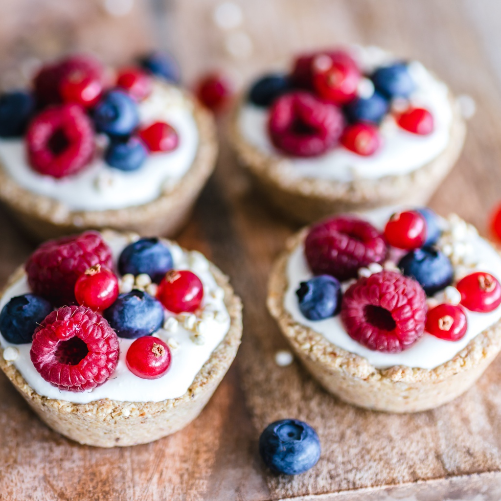 Пирожные с кремом и ягодами на столе крупным планом