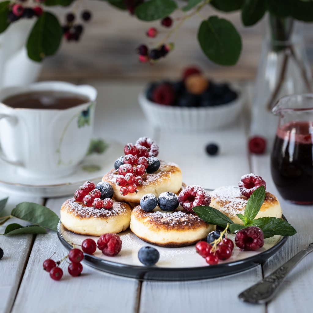 Сырники на столе с ягодами и чаем на завтрак