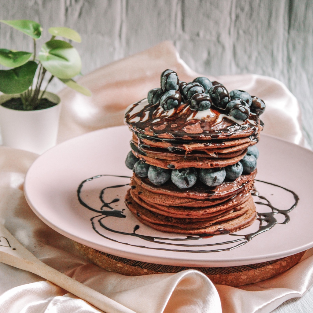 Шоколадные оладьи с ягодами черники на белой тарелке