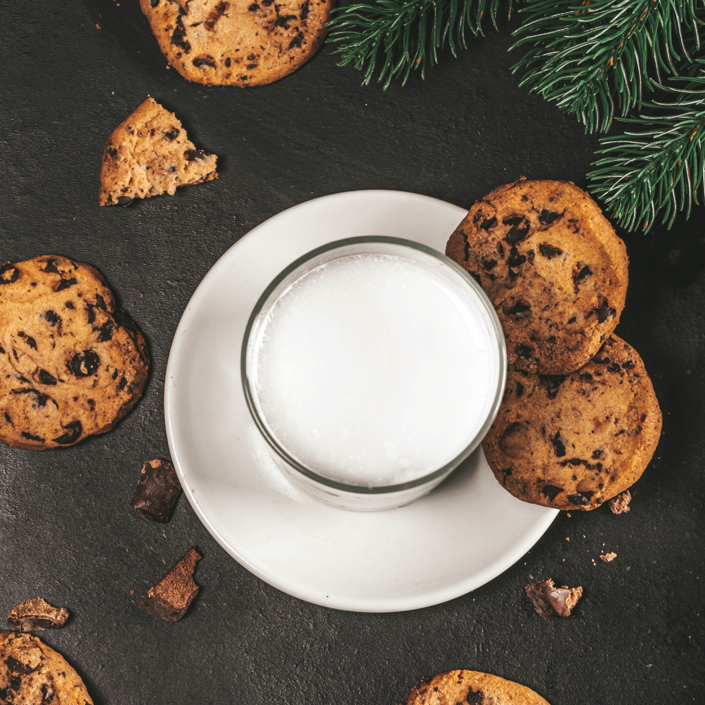 Печенье с шоколадом на столе со стаканом молока 