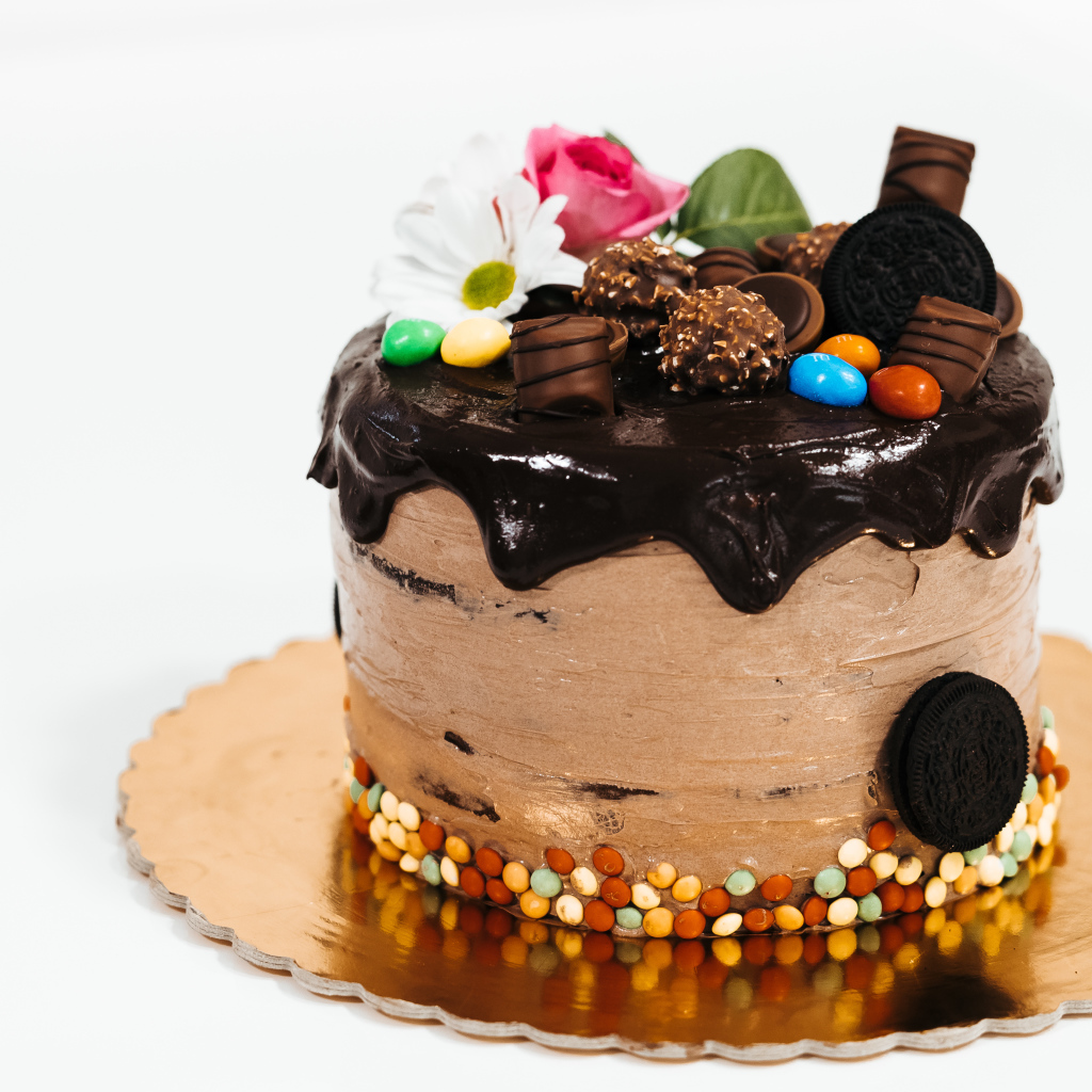 Торт с кремом и шоколадом украшен сладостями