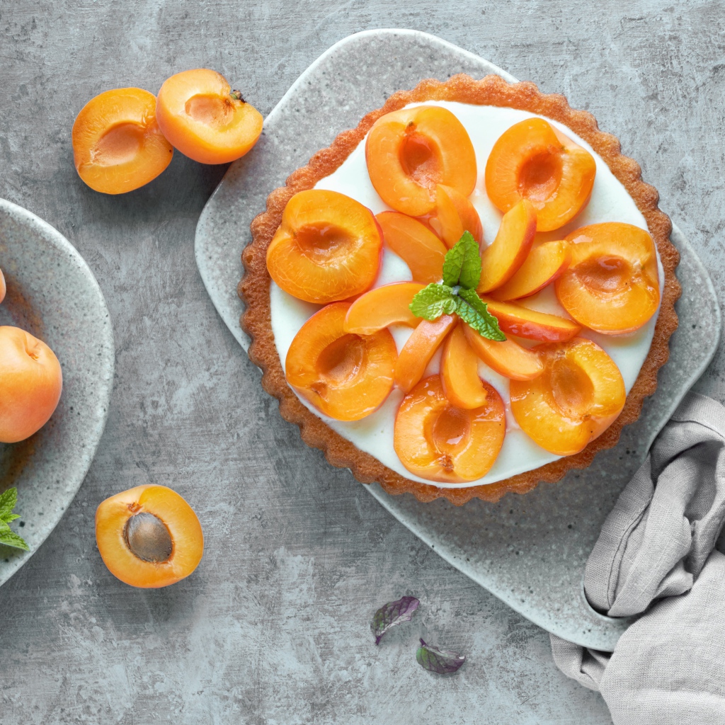 Пирог с кремом и абрикосами на столе 