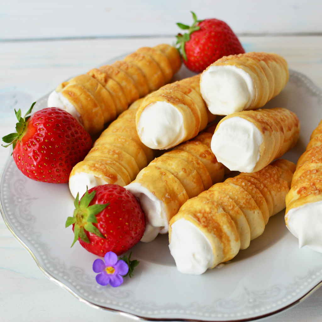 Пирожные с кремом на тарелке с клубникой