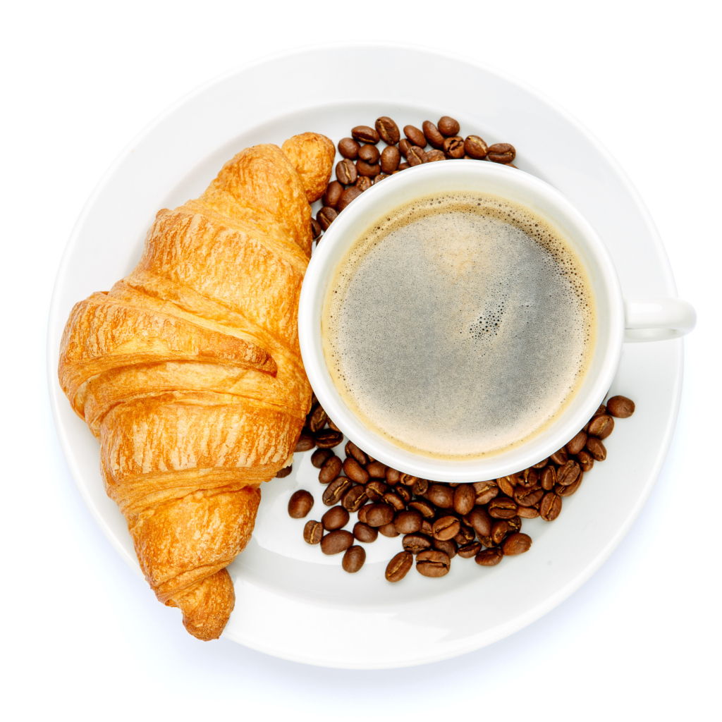 Чашка кофе на белой тарелке с круассаном и зернами, вид сверху 