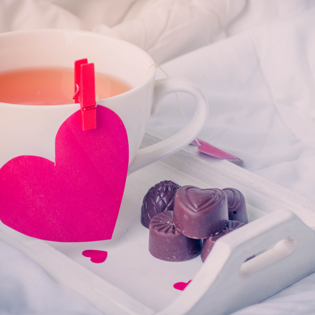 Чашка кофе с красным сердцем и шоколадными конфетами 