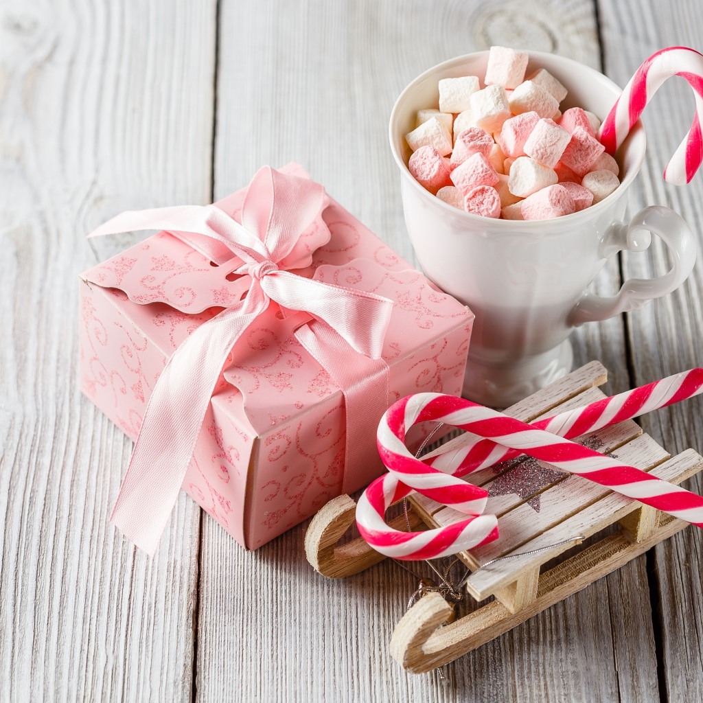 Чашка с маршмеллоу на столе с игрушечными санками и подарком