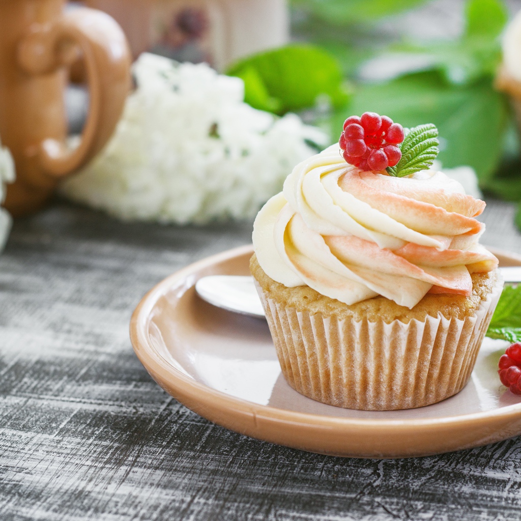 Кекс с кремом и малиной на столе