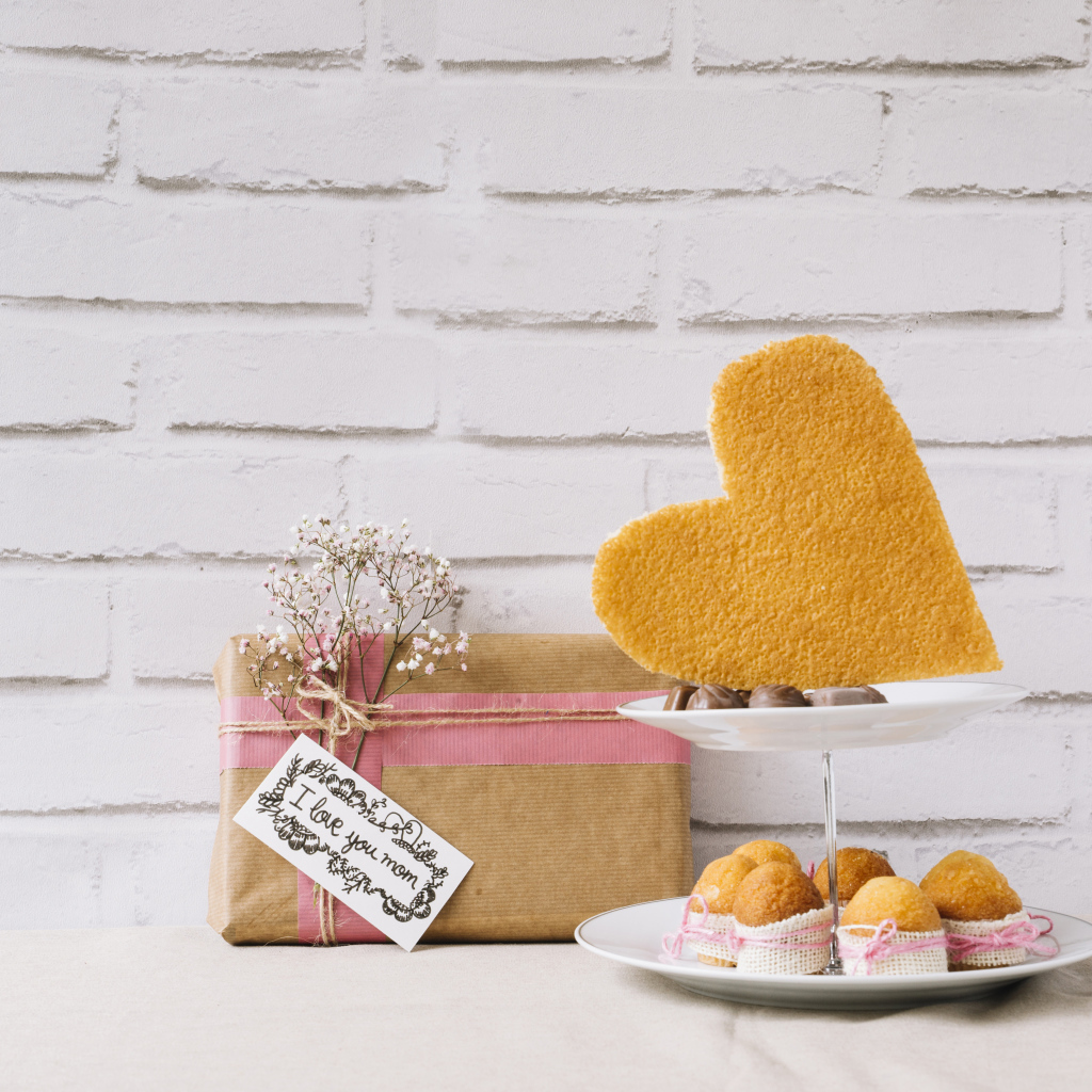 Кексы на тарелке на столе с подарком для любимой 