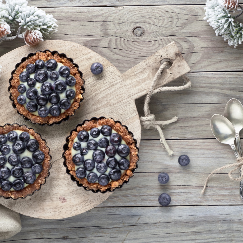 Кексы с кремом и ягодами черники на столе с чайными ложками