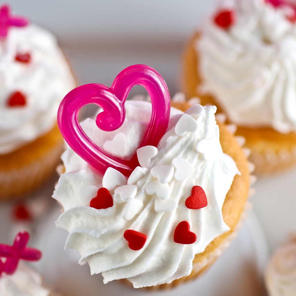 Кексы с кремом и сердечками на столе 