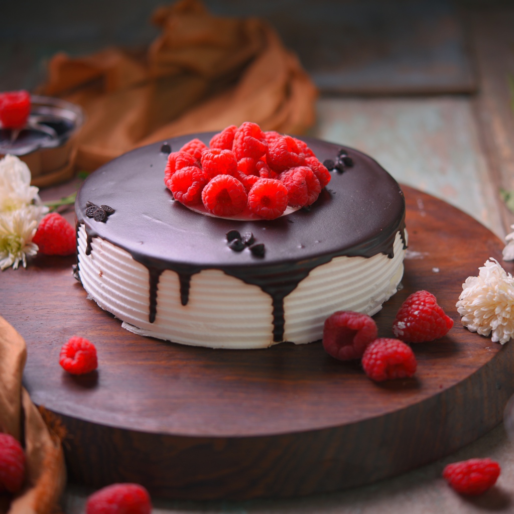 Вкусный торт с шоколадом и малиной на столе с цветами хризантемы 