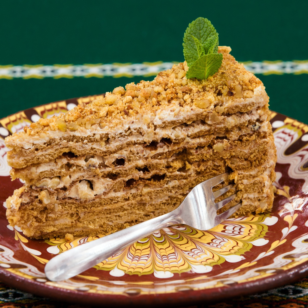 Вкусный медовый торт с орехами на красивой тарелке 