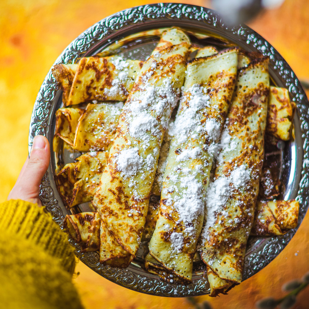 Вкусные тонкие блины с сахарной пудрой на блюде