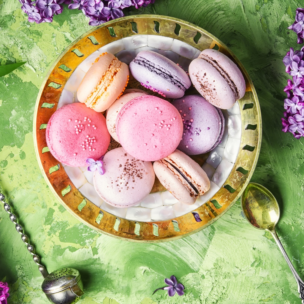 Разный десерт макарон на столе с цветами сирени 