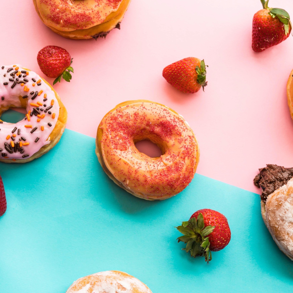 Пончики с глазурью на столе с ягодами клубники