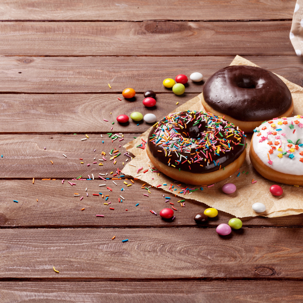 Пончики с глазурью на столе с конфетами на деревянном столе