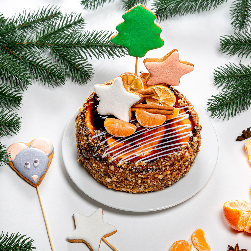 Праздничный торт на столе с мандаринами и еловыми ветками