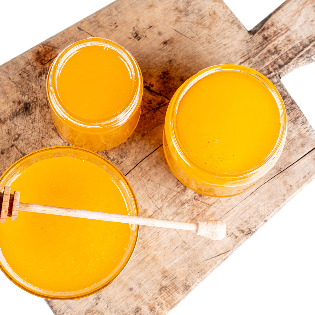 Свежий мед в банках на деревянной доске на белом фоне