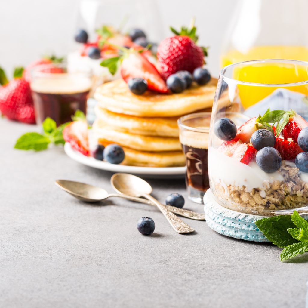 Оладьи на столе с ягодами, мюсли и кофе