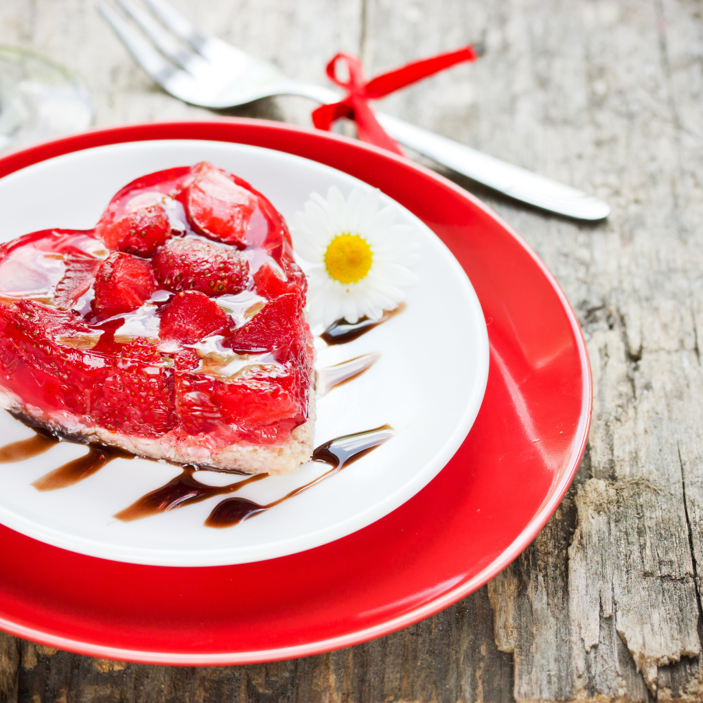 Пирожное с клубникой в форме сердца на тарелке с ромашками