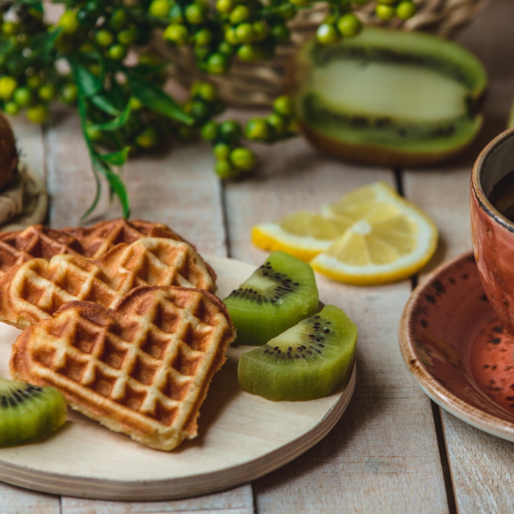 Вафли в форме сердца на доске с киви и чашкой кофе
