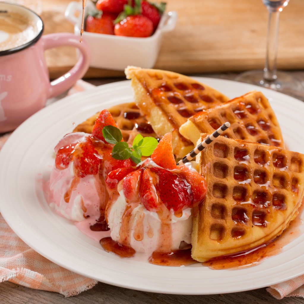 Шарики мороженого с клубникой на тарелке с вафлями и сиропом 