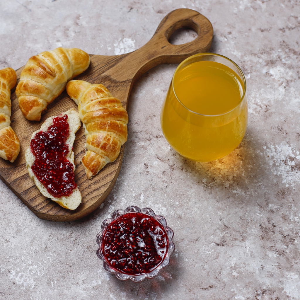 Сок на столе с круассанами и джемом