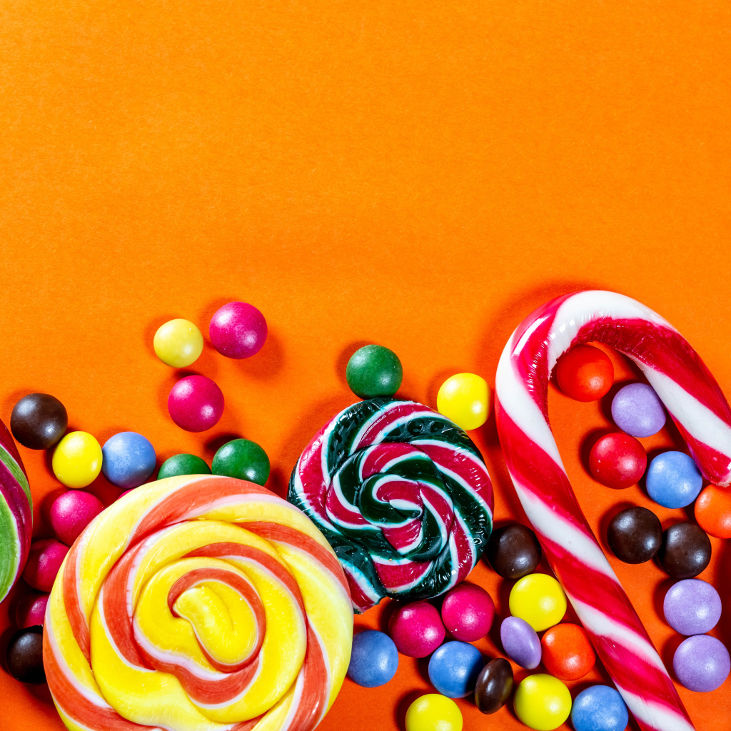 Разноцветные конфеты на оранжевом фоне