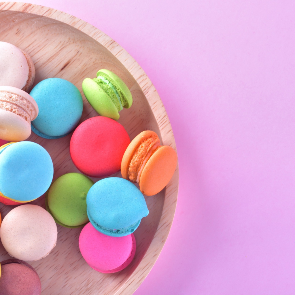 Разноцветное печенье макарон на розовом фоне вид сверху