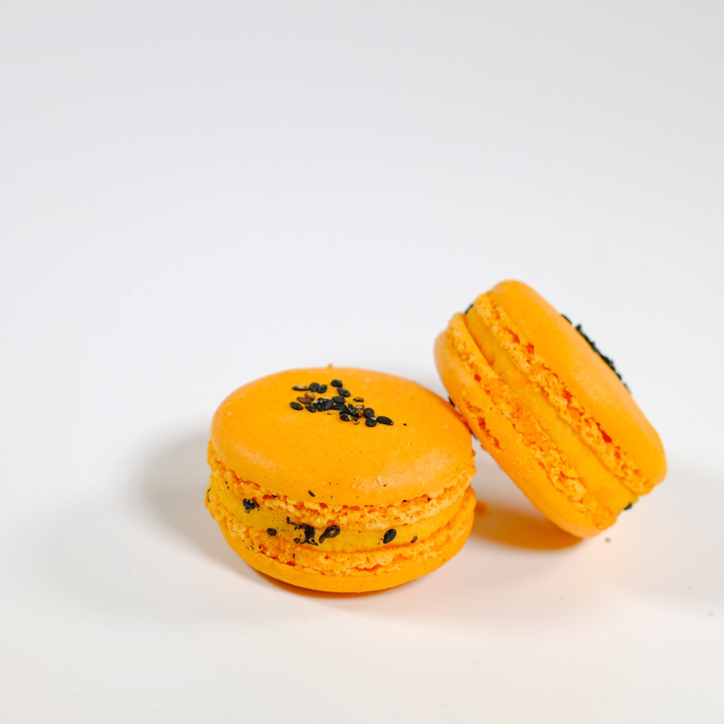 Оранжевый десерт макарон на сером фоне