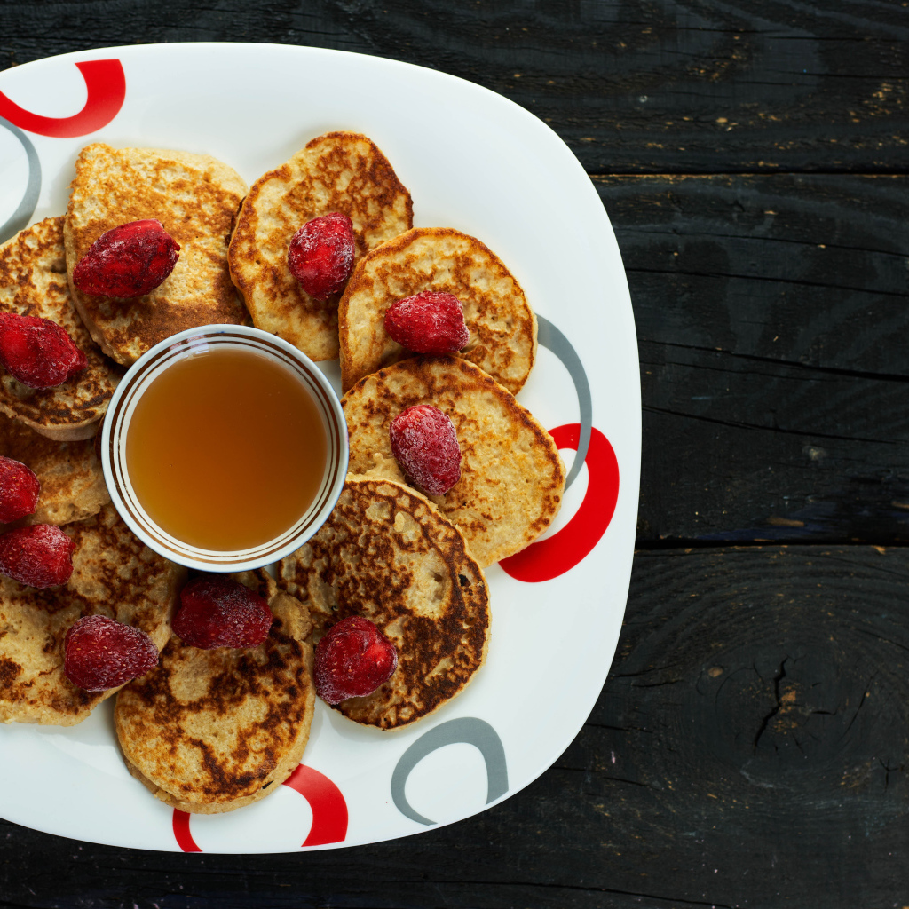 Оладьи на тарелке с клубникой и медом