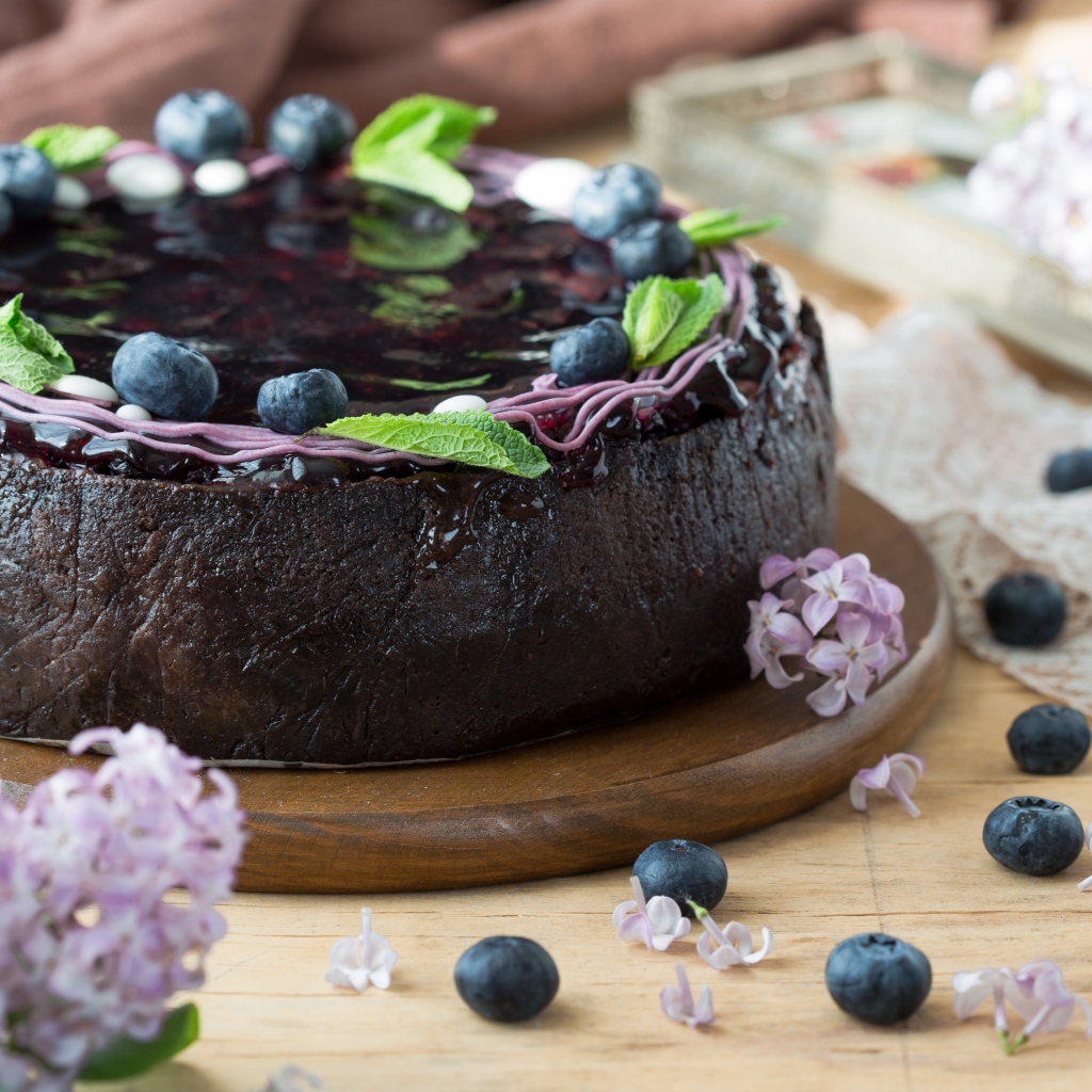Пирог с джемом и ягодами черники на столе с сиренью 