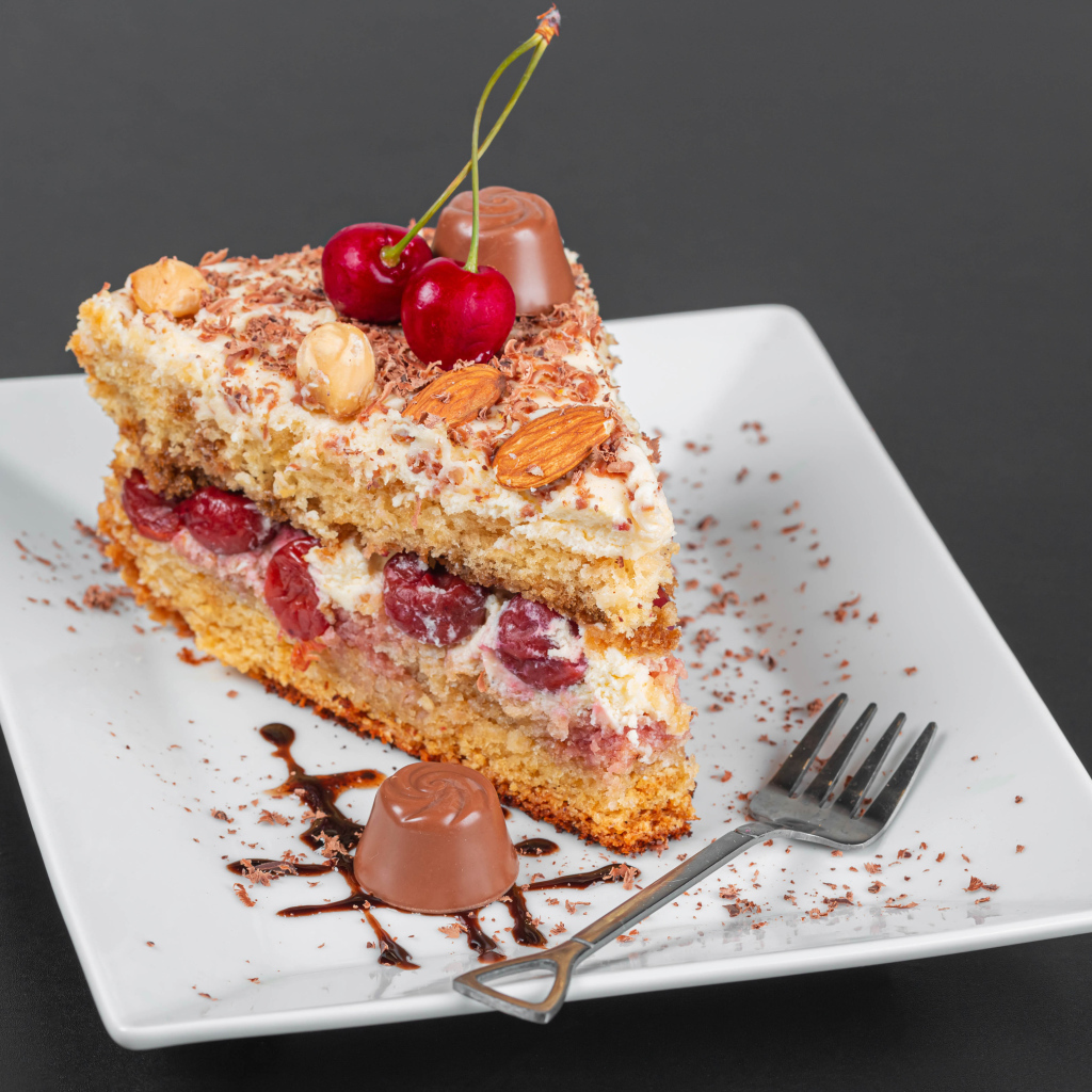 Кусок торта с ягодами вишни и миндальным орехом